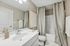 Elegant bathroom with sleek white fixtures, a large mirror, and tasteful decor creating a refreshing ambiance.