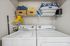 Convenient laundry room equipped with modern washer and dryer, featuring organized shelving with storage baskets and vibrant yellow hangers.