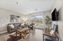 Inviting living room with cozy brown sofas, artistic wall decor, and a window offering scenic outdoor views. Modern wooden flooring complements the space, creating a warm and elegant atmosphere.