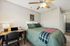 Cozy bedroom featuring a comfortable bed with green accents, a stylish desk setup, and a modern ceiling fan, perfect for a peaceful retreat.