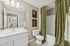 Elegant bathroom with modern fixtures, unique animal art, and luxurious green floral shower curtains.