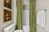 Charming bathroom featuring green patterned shower curtains, whimsical animal portraits, and a cozy, inviting ambiance.