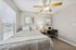Bright and modern bedroom with large windows, featuring a cozy bed, artistic decor, and a functional workspace.