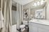 Modern bathroom with sleek lighting, elegant art, and crisp white fixtures.