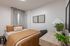 Cozy bedroom with a warm brown duvet, stylish decor, and ample natural light, complete with a sleek wooden desk and vibrant greenery.