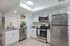 Modern kitchen with sleek stainless steel appliances, white cabinetry, and chic floating shelves in a bright open space.