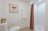 Bright and modern bathroom featuring elegant white tiles, a sleek toilet, and a stylish wicker basket for storage.