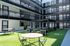 Modern apartment courtyard featuring stylish seating areas, lush green artificial turf, and contemporary architecture.