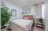 Bright and inviting bedroom with a cozy bed, elegant decor, and a lush green plant enhancing the serene atmosphere.