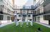 Modern apartment complex featuring an open-air courtyard gym with state-of-the-art fitness equipment on a lush green synthetic turf.