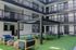 Modern apartment courtyard featuring stylish seating, vibrant green synthetic grass, and a ping pong table under a chic canopy.