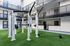 Modern apartment courtyard featuring a premium outdoor gym with state-of-the-art exercise equipment on lush green turf.