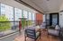 Chic urban balcony with cozy seating and vibrant rug, overlooking modern apartment complex.