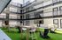Modern apartment courtyard with stylish seating and lush artificial grass, surrounded by sleek balconies.