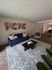Inviting living room with a modern blue sofa, chic abstract wall art, and a stylish black coffee table on a textured rug.