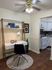 Chic home office setup with a modern desk and stylish chair, adjacent to a cozy kitchen with white cabinets and classic appliances.