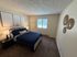 Inviting bedroom with modern decor, featuring a plush bed with navy bedding, stylish wall art, and warm ambient lighting.
