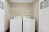 Modern laundry room featuring a white washer and dryer set with overhead shelving, perfect for efficient home living.