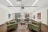 Modern lobby area with stylish green armchairs, abstract art, and ample natural light.