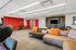 Contemporary lounge area featuring vibrant orange accents, sleek seating, and modern decor under a bright, well-lit ceiling.