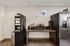 Modern apartment amenity offering a sleek coffee station with a variety of flavored syrups, a premium beverage machine, and stylish stainless steel fridge.