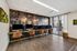 Modern co-working space with sleek iMac stations, stylish leather chairs, vibrant speaker-themed wall, and natural light from large windows.