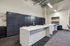 Modern package delivery room with secure lockers, sleek white tables, leather chairs, and vibrant wall art, bathed in natural light.