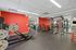 Modern fitness room equipped with state-of-the-art workout machines, vibrant red walls, and ample natural light.