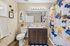 Bright and modern bathroom with elegant vanity, chic wall art, and colorful shower curtain for a stylish ambiance.