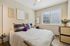 Inviting bedroom with cozy decor, featuring a plush bed, elegant wall art, and a large window allowing natural light.