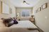 Cozy bedroom with elegant decor, featuring a plush bed and framed art, bathed in natural light from a large window.