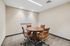 Modern conference room featuring a sleek round table with four stylish leather chairs, perfect for collaborative meetings in a sophisticated office setting.