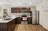 Modern kitchen with sleek stainless steel appliances, elegant dark wood cabinets, and a spacious countertop complemented by warm wood flooring.