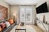 Chic living room with modern decor, featuring a comfortable sofa with vibrant pillows, large TV, elegant artwork, and bright double doors opening to a beautiful view.