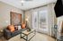 Chic living room with a modern grey sofa, vibrant orange cushions, and natural light streaming through French doors, creating a cozy ambiance.