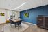Chic modern conference room with vibrant blue accent wall, stylish wooden table, and natural light from large window.