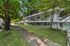 Charming apartment building nestled among lush trees, featuring spacious balconies and a well-maintained grassy pathway.
