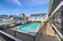 Inviting apartment complex with a sparkling pool, surrounded by modern buildings under a clear blue sky.