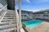 Inviting apartment complex with sunlit central pool, surrounded by charming multi-level wooden staircases and railings.