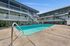 Inviting apartment complex with a sparkling outdoor pool, surrounded by modern balconies and lush greenery.