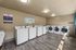 Modern laundry room with multiple high-efficiency washers and dryers on sleek flooring, ample space and bright lighting.
