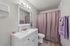 Elegant bathroom with modern fixtures, featuring a sleek white vanity, large mirror, and soft lavender accents for a serene atmosphere.