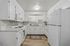 Bright and modern kitchen with sleek white cabinetry, contemporary appliances, and elegant wood flooring.