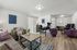 Inviting living space with modern furniture, cozy seating, and natural light streaming through large blinds, perfect for relaxation and productivity.
