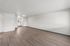 Spacious open floor plan featuring modern hardwood floors, a bright kitchen nook, and crisp white walls.