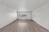 Bright and spacious living room with expansive windows and sleek hardwood floors, perfect for relaxation and entertainment.