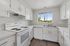 Bright and modern kitchen with sleek white cabinetry, electric stove, and a scenic view from the window.