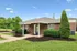 Charming brick home with lush landscaping and a cozy covered porch, perfect for tranquil living.