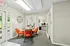 Bright and inviting meeting space featuring modern decor, orange chairs, and a large window overlooking a lush garden.