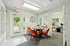 Charming office space with vibrant orange chairs around a round table, large windows for natural light, and a welcoming view of greenery through the glass doors.